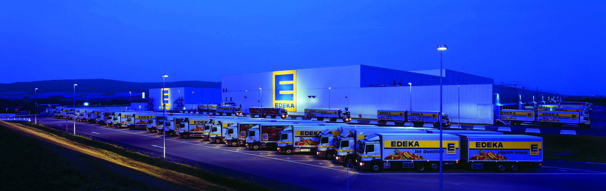 Edeka trucks at distribution center during night.