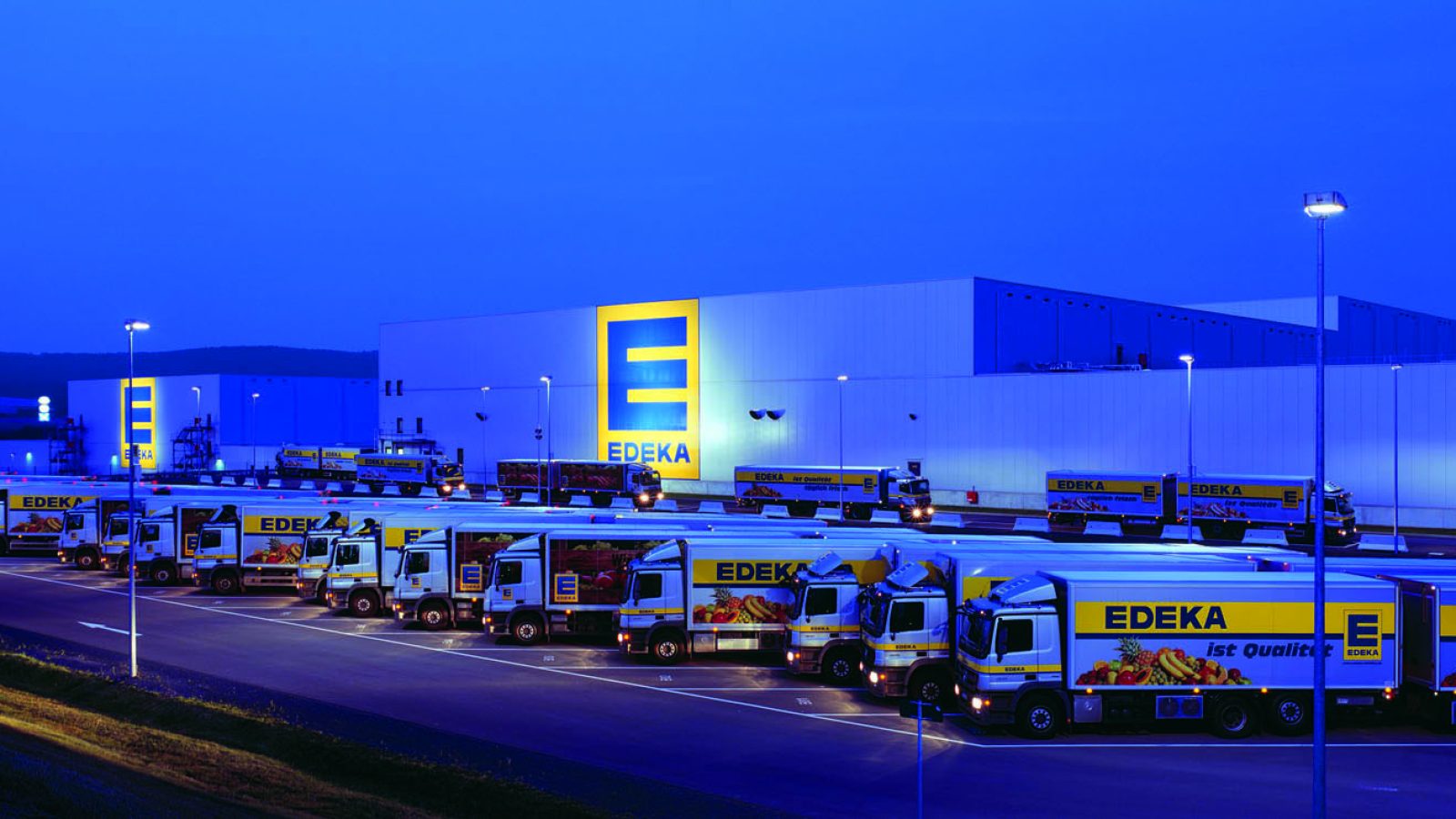 Edeka trucks at distribution center during night.