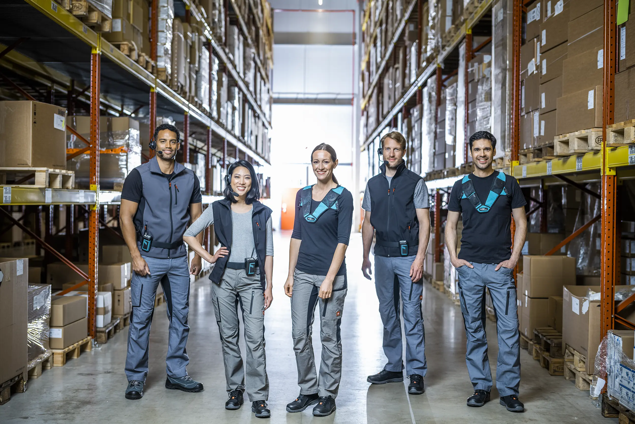 Warehouse staff posing in aisle with headsets.